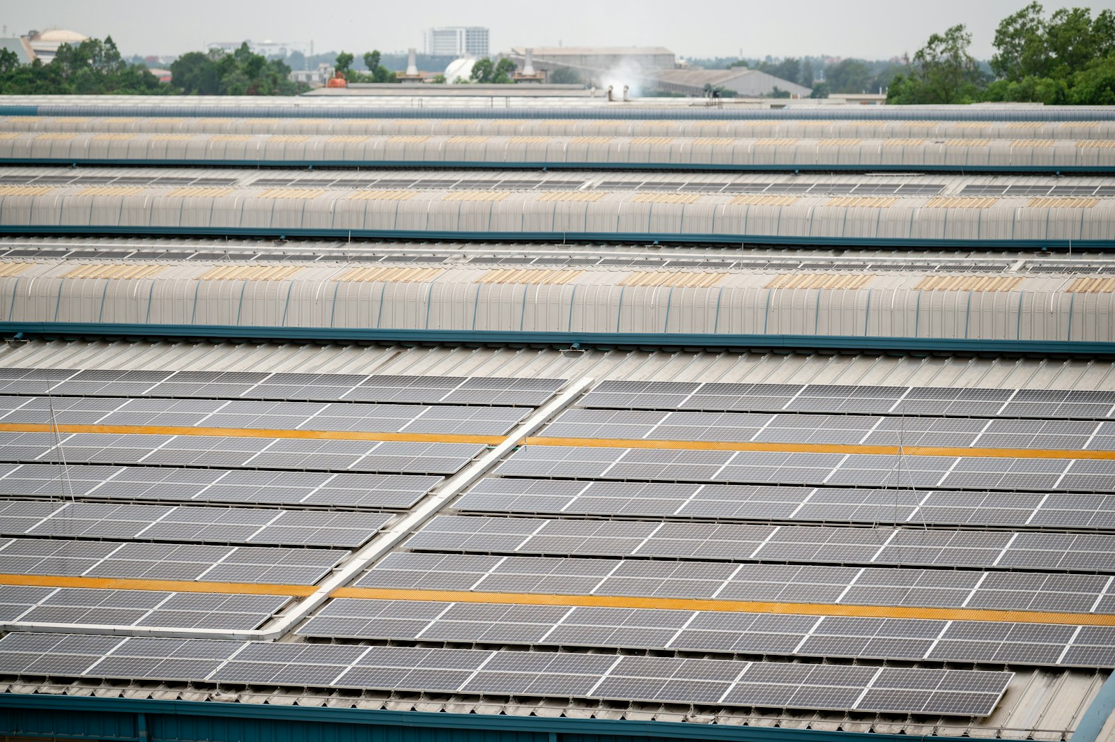 Solceller på ett stort industritak med sågtakstegel i bakgrunden under klar himmel